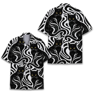May include: Two short-sleeved button-down shirts with a black cat and white swirl pattern. The cats have yellow eyes and are set against a black and white background. The shirts are a casual style.