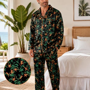 May include: A black pajama set featuring a repeating pattern of orange monkeys and green palm leaves. The long-sleeve button-down shirt has an orange piped collar and front placket, matching the long trousers with a consistent jungle-themed print.