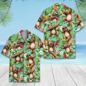 Puede incluir: Una camisa de manga corta con un estampado tropical. La camisa presenta un patrón de perezosos con gafas de sol, piñas y flores sobre un fondo turquesa. Una camisa a juego es visible en el fondo.