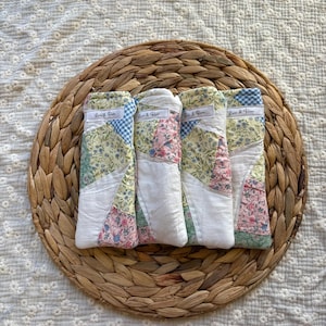 May include: Four rectangular fabric pouches featuring a patchwork design of floral, gingham, and solid white cotton panels. Each pouch has a small white label with the text "Lois & Rose" stitched near the top edge, showcasing varied pastel colors.
