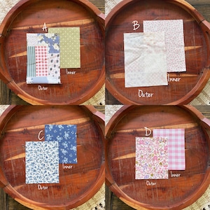Puede incluir: Cuatro conjuntos de muestras de tela dispuestas sobre una bandeja de madera. Cada conjunto incluye una pieza de tela "exterior" y una pieza "interior". Las telas presentan varios patrones, incluyendo dise&ntilde;os florales, lunares, rayas y patchwork. La paleta de colores incluye azul, rosa y verde.