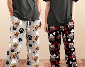 May include: Two pairs of pajama pants with dog-themed patterns. One pair is light gray with golden retriever faces and paw prints. The other is black with pug faces and red hearts. Both people are wearing gray t-shirts.