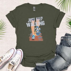 May include: A green t-shirt with the text "JUST KEEP WALKING" in white letters. A cartoon illustration of a person's leg and foot walking is below the text.