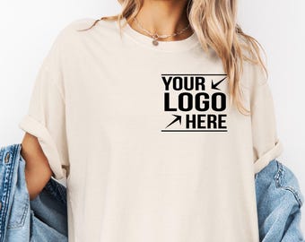 May include: A beige t-shirt with a black box that says "YOUR LOGO HERE" with an arrow pointing to the right and a checkmark pointing down.