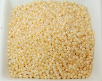 May include: A close-up image of a bowl filled with small, round, cream-colored beads. The beads have a slight iridescent sheen.
