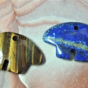 May include: Two carved stone bear pendants, one with tiger's eye and one with lapis lazuli. Both pendants have a hole for a cord.