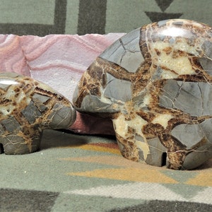May include: Two carved stone bear figurines, one larger than the other, with a brown, gray, and white marbled pattern.