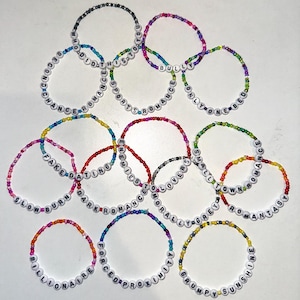 Puede incluir: Una colección de pulseras de cuentas coloridas con diferentes palabras escritas en ellas, incluyendo "Slow Burn", "Fake Dating", "Bully Romance", "Small Town Romance", "Enemy to Lovers", "Forced Proximity", "Grumpy Sunshine", "Billionaire", "This is Sports", "Morally Grey", "Only One Bed", "Chance Romance", "Who Did This to You".