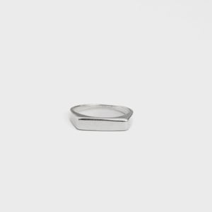Può includere: Un anello color argento lucido caratterizzato da una superficie superiore piatta e rettangolare e da una fascia liscia e continua. Il metallo ha una finitura riflettente e il design è definito da bordi netti, dritti e una forma semplice.