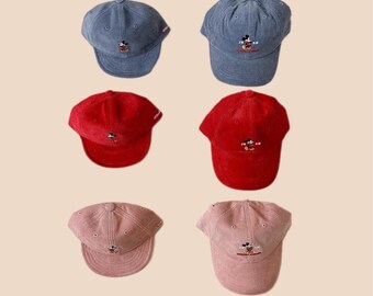 May include: Ten corduroy baseball caps with an embroidered Mickey Mouse design. The caps are in various colors, including green, blue, red, pink, and beige.