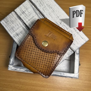 May include: A handcrafted, brown leather case with a perforated front and a flap secured by a brass button. The case is placed inside a rustic, white-washed wooden box. The PDF icon is visible in the background.