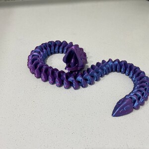 Op de afbeelding: Een 3D-geprinte gesegmenteerde slang in paars en blauw met een textuur.