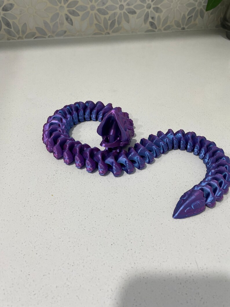 Op de afbeelding: Een 3D-geprinte gesegmenteerde slang in paars en blauw met een textuur.