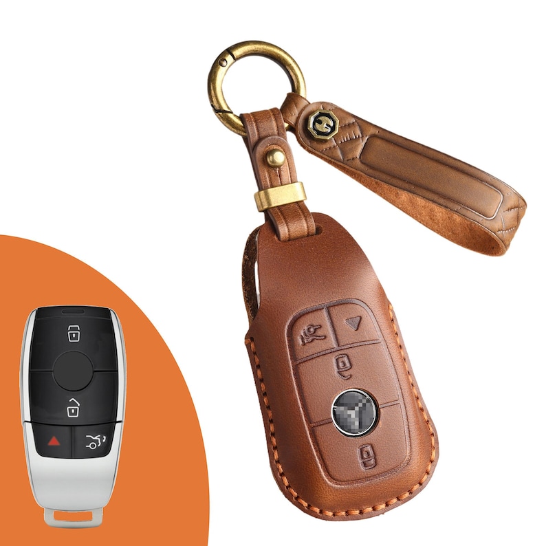 May include: Brown leather car key fob cover with a gold-colored keyring and strap. The cover has embossed buttons and a logo. A separate car key is also visible.