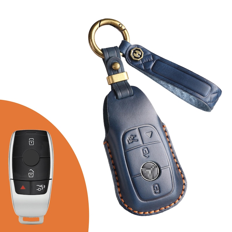 May include: A blue leather car key fob cover with a gold-colored keyring and strap. The key fob cover has a stitched border and a metal clasp. The key fob is shown next to a car key.