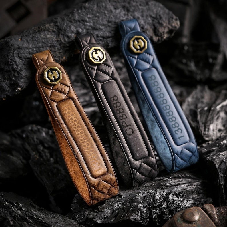 May include: Three leather keychains in brown, black, and blue, each with a quilted pattern and a gold-colored emblem. The brown keychain has the number "1388888888" embossed, the black one has "CP8888", and the blue one has "1388888888".