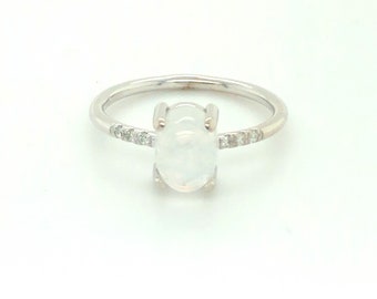 May include: A silver ring with a white oval gemstone and a row of small diamonds around the band.