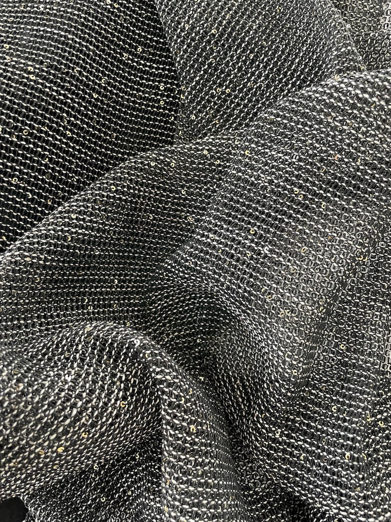 May include: Black fabric with a fine, woven texture and a subtle shimmer from gold sequins.