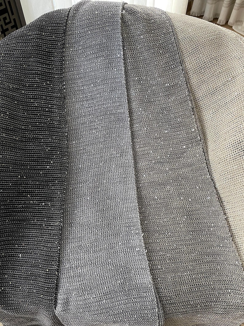 May include: A close-up of a woven throw blanket with three sections in shades of grey. The blanket is made of a soft, textured material.