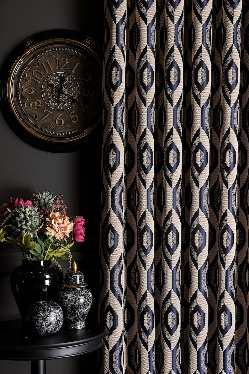 May include: Elegant, patterned curtains in beige and navy blue with a geometric design. A dark, round clock with gold accents hangs on the wall. A black vase holds colorful flowers, adding a touch of vibrancy.