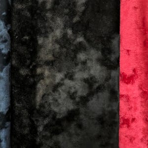 K&ouml;nnte beinhalten: Drei rechteckige Stoffmuster mit einer pl&uuml;schigen, strukturierten Oberfl&auml;che. Das linke Muster ist dunkelblau, das mittlere schwarz und das rechte leuchtend rot. Jeder Stoff weist einen weichen, samtigen Flor mit einer dezenten, melierten Optik auf.