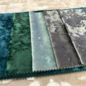 K&ouml;nnte beinhalten: Ein Stoffmusterbuch mit einem Farbverlauf aus zerknitterten Samttexturen in den Farbt&ouml;nen Dunkelblau, Waldgr&uuml;n, Petrol, Hellblau und Anthrazit. Jeder rechteckige Stoffstreifen hat gezackte Kanten und einen ausgepr&auml;gten, reflektierenden Glanz.