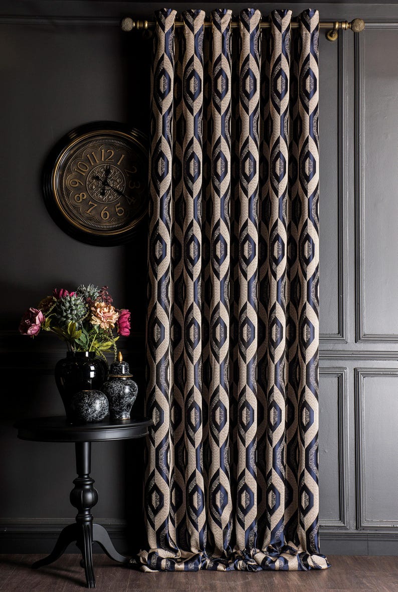 May include: Elegant navy blue and beige patterned curtains hanging in front of a dark gray wall. A black side table holds a vase of flowers and decorative jars. A gold-framed clock hangs on the wall.