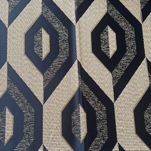 May include: Geometric patterned fabric featuring repeating navy blue and beige diamond shapes. The design has a textured appearance with a woven effect, creating a modern and stylish aesthetic. The fabric is suitable for upholstery or decorative projects.