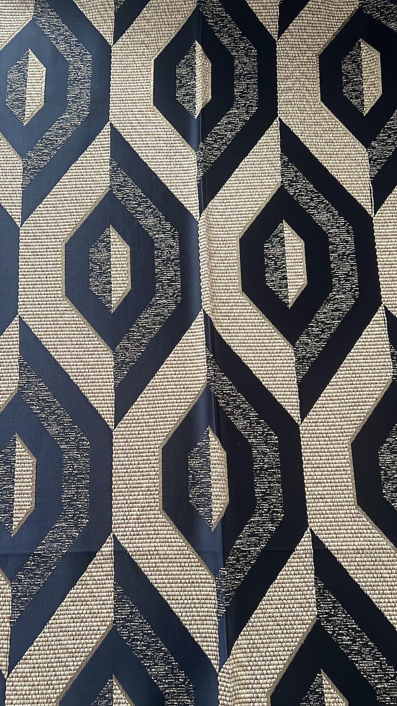 May include: Geometric patterned fabric featuring repeating navy blue and beige diamond shapes. The design has a textured appearance with a woven effect, creating a modern and stylish aesthetic. The fabric is suitable for upholstery or decorative projects.