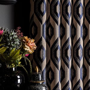 May include: Textured beige and navy blue geometric patterned curtains. The curtains have a repeating diamond-like design. A black clock and vases with flowers are in the background.