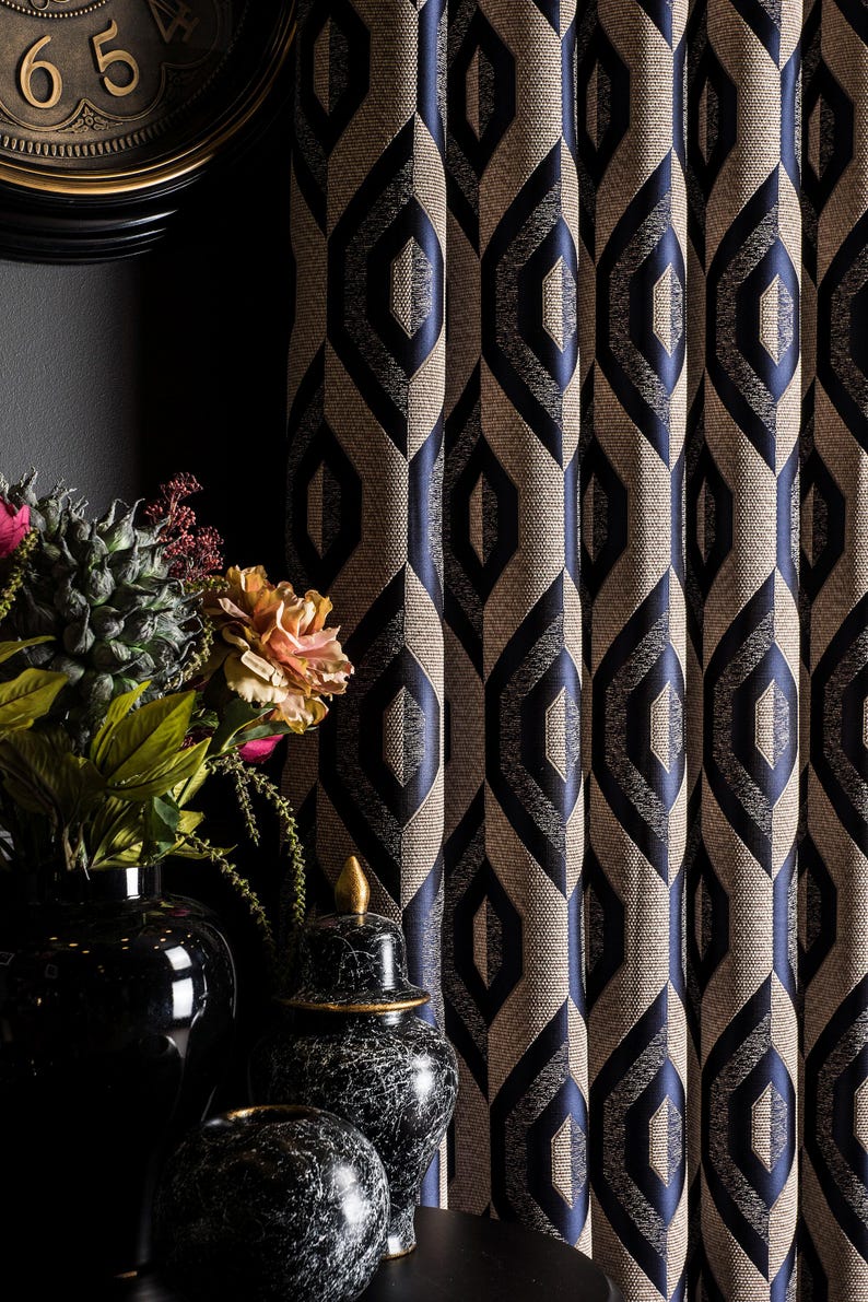 May include: Textured beige and navy blue geometric patterned curtains. The curtains have a repeating diamond-like design. A black clock and vases with flowers are in the background.