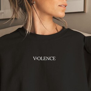 Pu&ograve; includere: Felpa nera oversize con la parola "VIOLENCE" ricamata in bianco sul davanti.