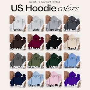 May include: A color chart displaying sixteen hooded sweatshirts in various shades including white, ash, sport grey, dark heather, choc brown, maroon, black, sand, charcoal, military green, forest, carolina blue, navy, light blue, light pink, and purple.
