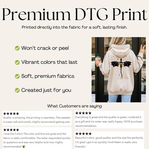 Puede incluir: Una sudadera con capucha de color beige que presenta un gr&aacute;fico de un drag&oacute;n negro en la espalda. La imagen incluye el texto Premium DTG Print, Printed directly into the fabric for a soft, lasting finish y rese&ntilde;as de clientes con cinco estrellas.