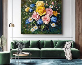 May include: An oil painting depicting a colourful floral arrangement. The bouquet includes yellow and pink roses, blue hydrangeas, and white daisies, set against a dark green backdrop. The artwork is in a gold frame and hangs above a green velvet sofa in a living room.