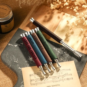 May include: Five personalized metal and wood smoking pipes with different colored finishes and engraved text. The text includes "Love You Forever", "RS", "Theodore", and "Allan Woodman".