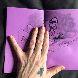 以下が含まれることがあります： 紫色のページに黒インクで描かれた、抱擁する2人の人物のスケッチ。アートワークは開かれており、イラストが明らかになっています。アーティストのイニシャルと2015年が右下に表示されています。