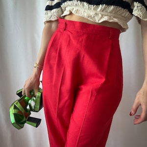 Puede incluir: Pantalón rojo de cintura alta con pierna ancha y top corto a rayas.