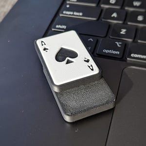 Office Spielzeug, der Ass Fidget Slider. Der Slider liegt auf einem Macbook.