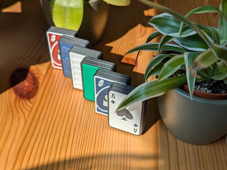May include: A set of six playing cards with different symbols and colors. The cards are arranged in a row, with the Ace of Spades at the end. The cards are made of a durable material and have a smooth, matte finish.