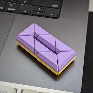 May include: A purple and yellow geometric puzzle made of interlocking triangular pieces.