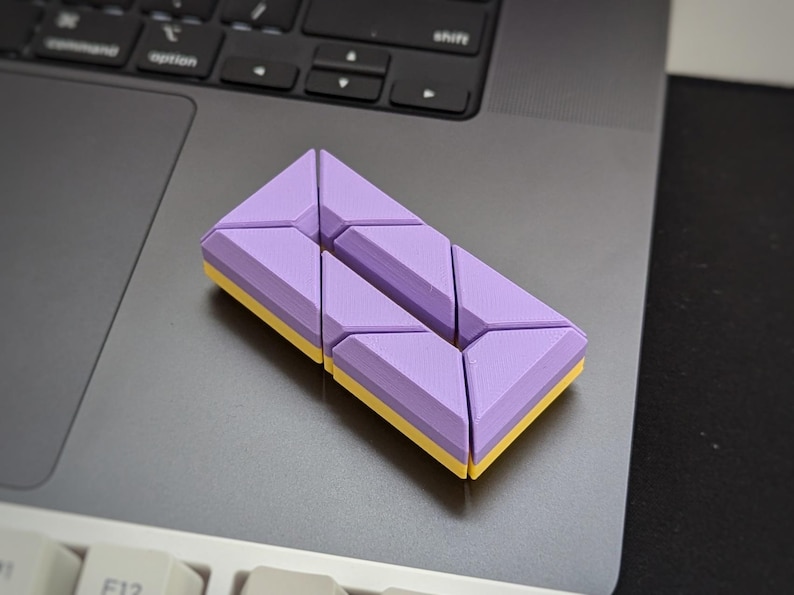 May include: A purple and yellow geometric puzzle made of interlocking triangular pieces.