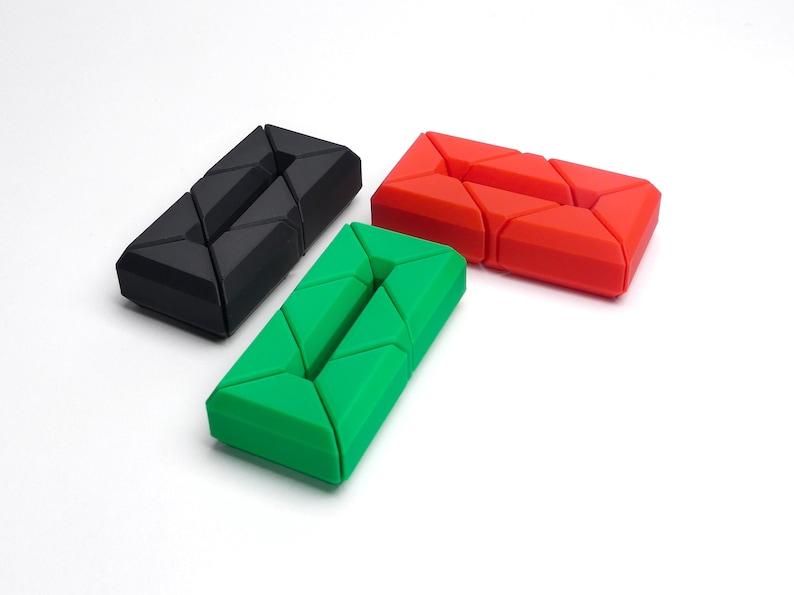 May include: Three geometric puzzle toys in black, green, and red. Each toy is made of interlocking pieces that can be rearranged into different shapes.
