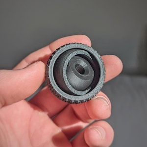 Może przedstawiać: Czarna, 3D-drukowana głowica kulowa z gwintowanym otworem w środku. Głowica kulowa ma teksturę i jest przeznaczona do użytku ze statywem.