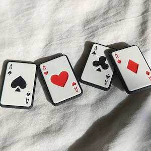 Alle 4 Varianten des Poker Sliders nebeneinander. Pik, Herz, Kreuz und Karo liegen drappiert auf einem weißen Tuch.