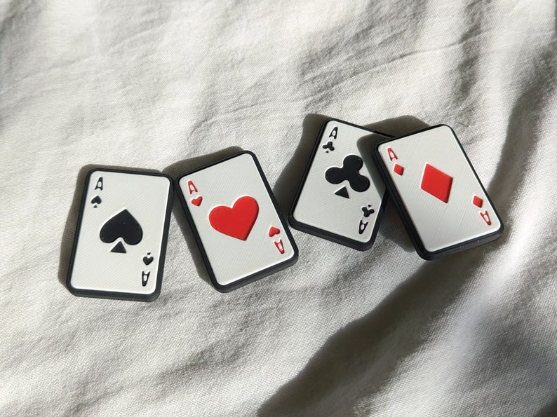 Alle 4 Varianten des Poker Sliders nebeneinander. Pik, Herz, Kreuz und Karo liegen drappiert auf einem weißen Tuch.