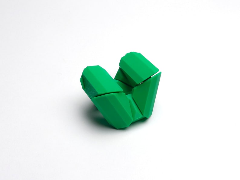 May include: A green geometric puzzle toy with multiple interlocking pieces. The toy is made of plastic and is designed to be folded and unfolded.