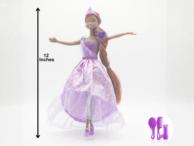 May include: A doll, approximately 12 inches tall, wearing a lavender dress with a white floral pattern and a sheer overlay. The doll has long brown hair and is accessorized with a crown and a sash. A set of purple hair accessories is included.