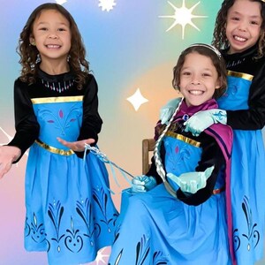 Girls dress in birthday outfit in a princess birthday party theme home, girls dressed up in elsa coronation dress costume for Halloween. The girls wear tiara, playful magic wand, and princess gloves. The background has sparkling stars