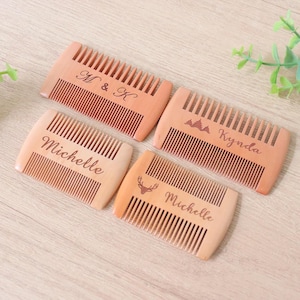 May include: Four wooden combs with engraved designs and text. One comb has "M & K", another has "Michelle", a third has a mountain design and "Kynda", and the last has a deer and "Michelle".